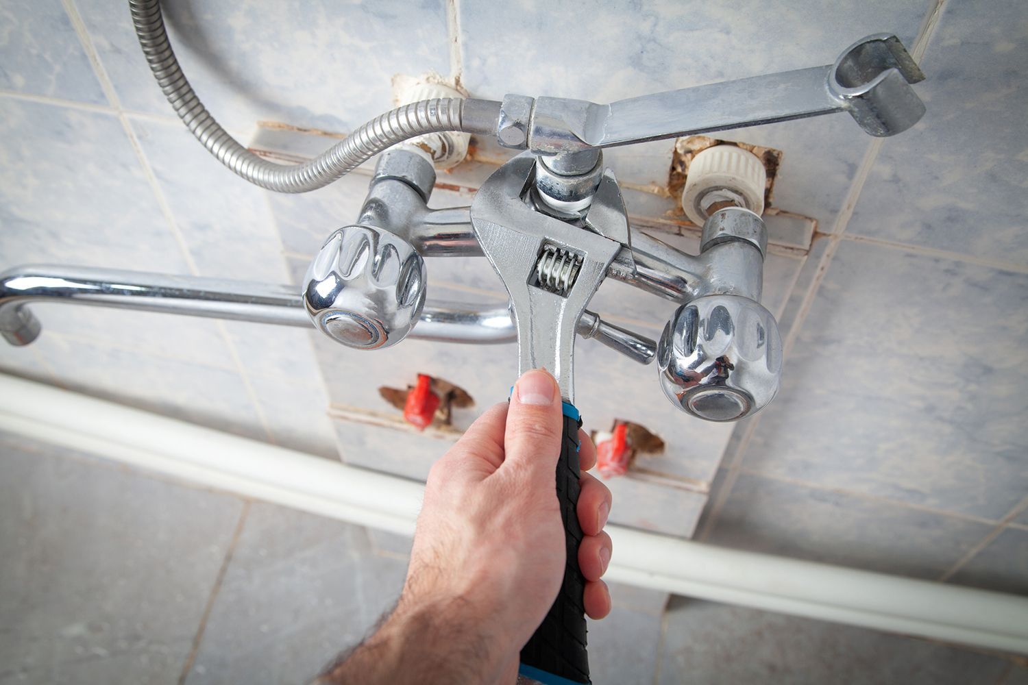 A person is fixing a faucet with a wrench.