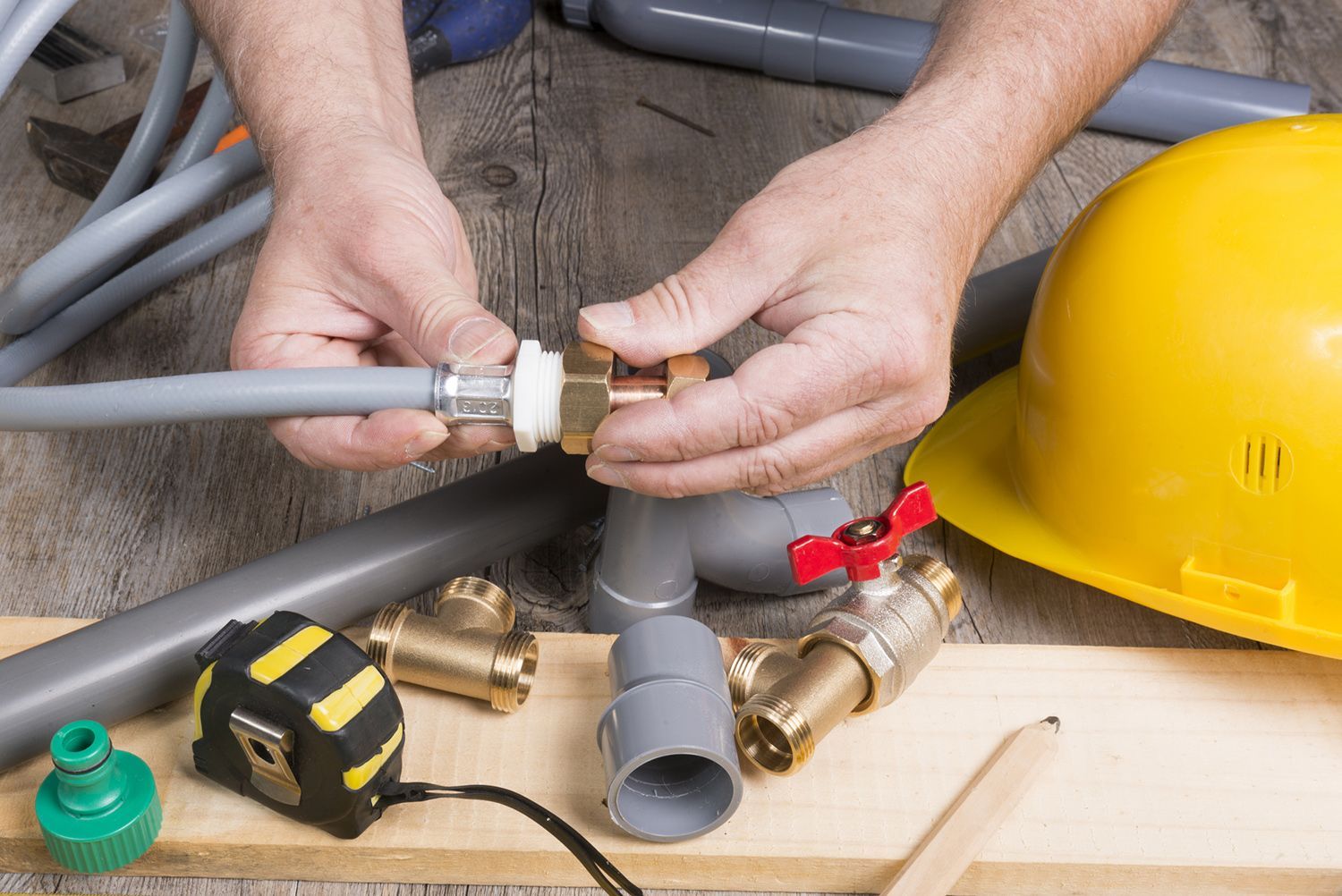 A plumber is working on a pipe on a wooden table.