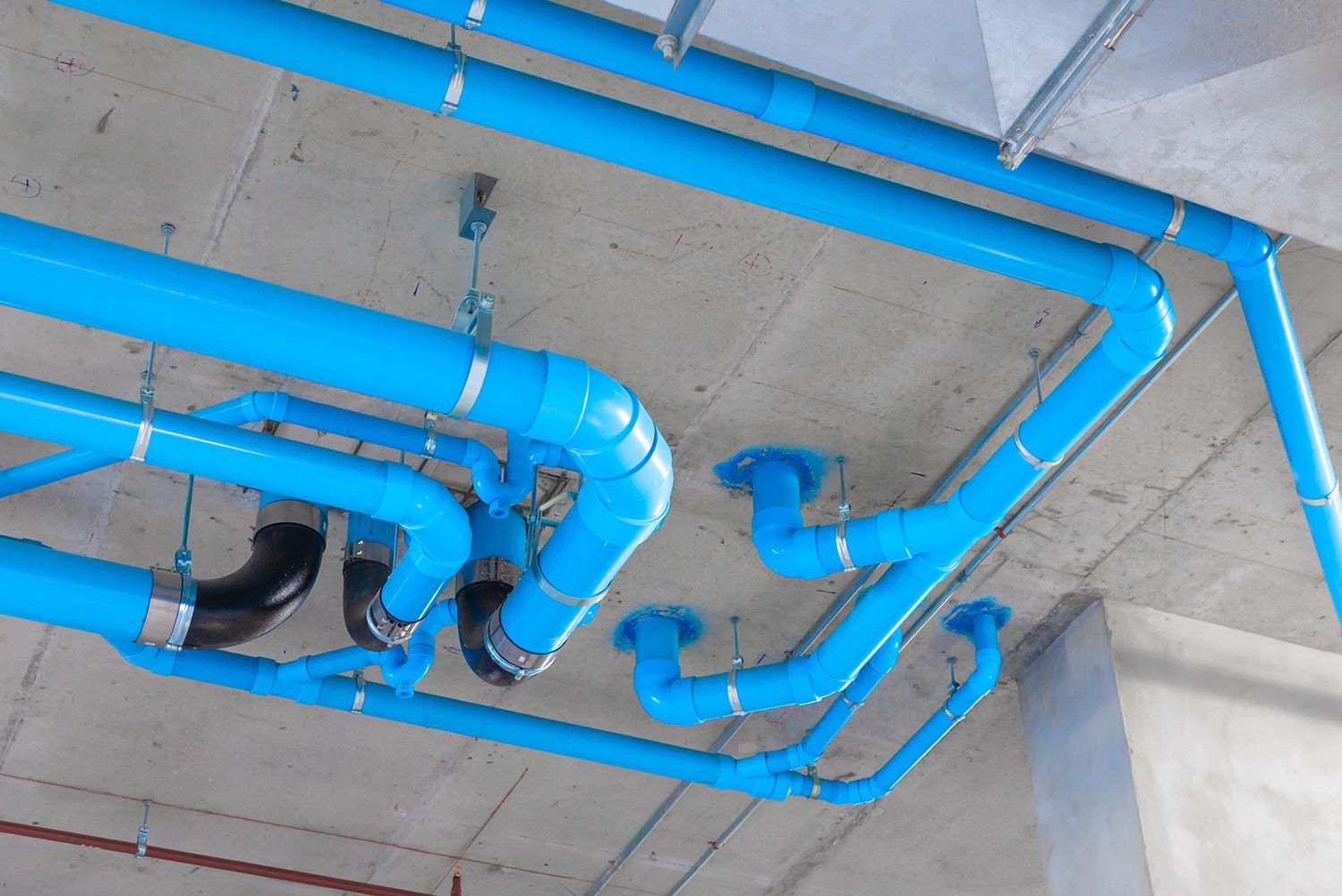A bunch of blue pipes are hanging from the ceiling of a building.