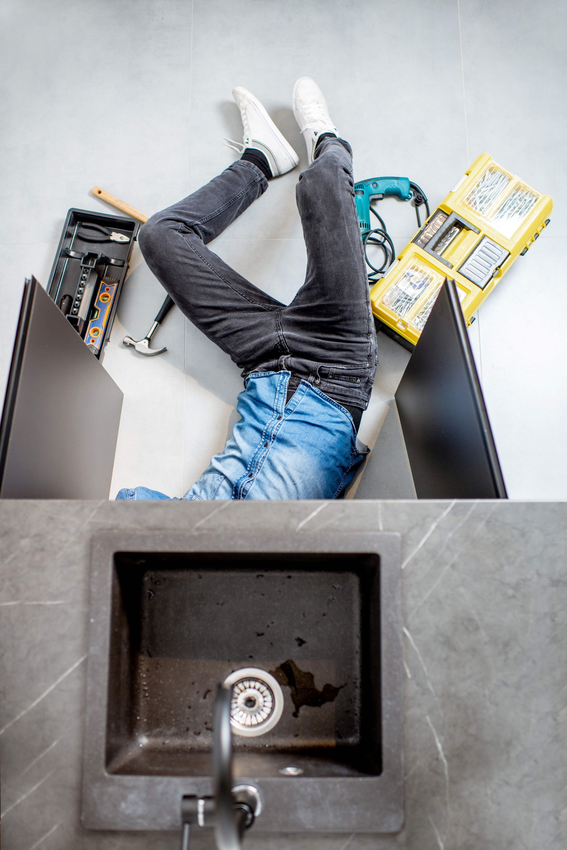 A plumber performs residential plumbing services, repairing a kitchen sink. 