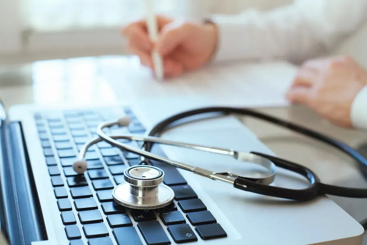 A stethoscope is sitting on top of a laptop keyboard.