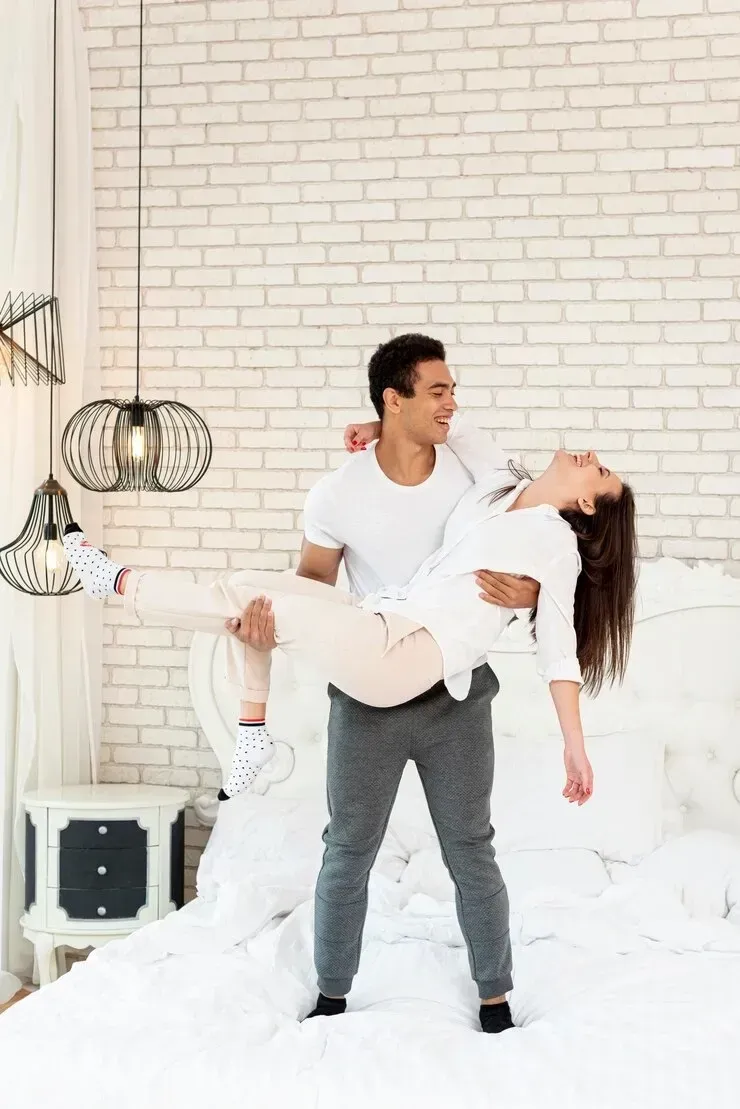A man is holding a woman in his arms on a bed.