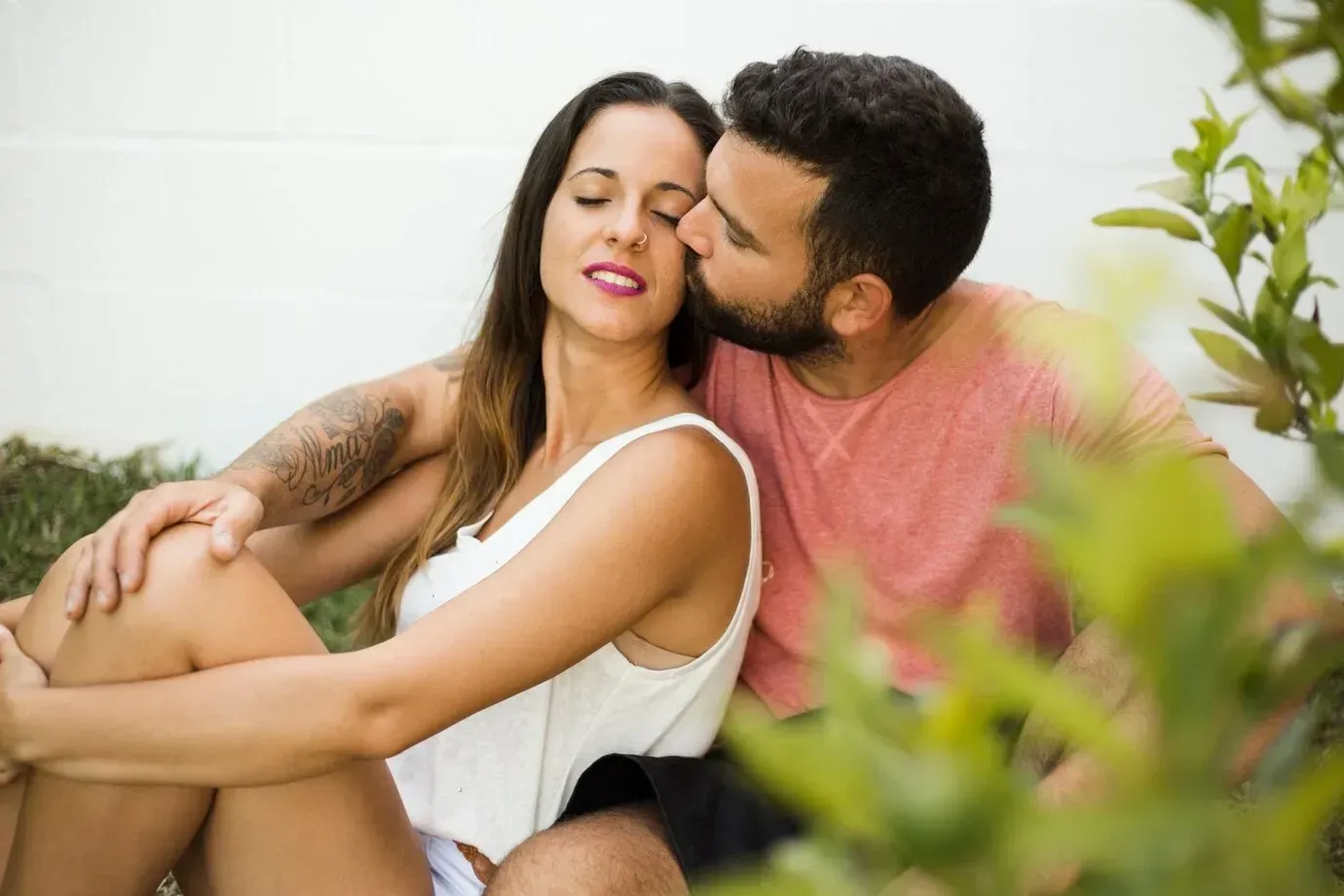 A man is kissing a woman on the cheek while sitting next to her.