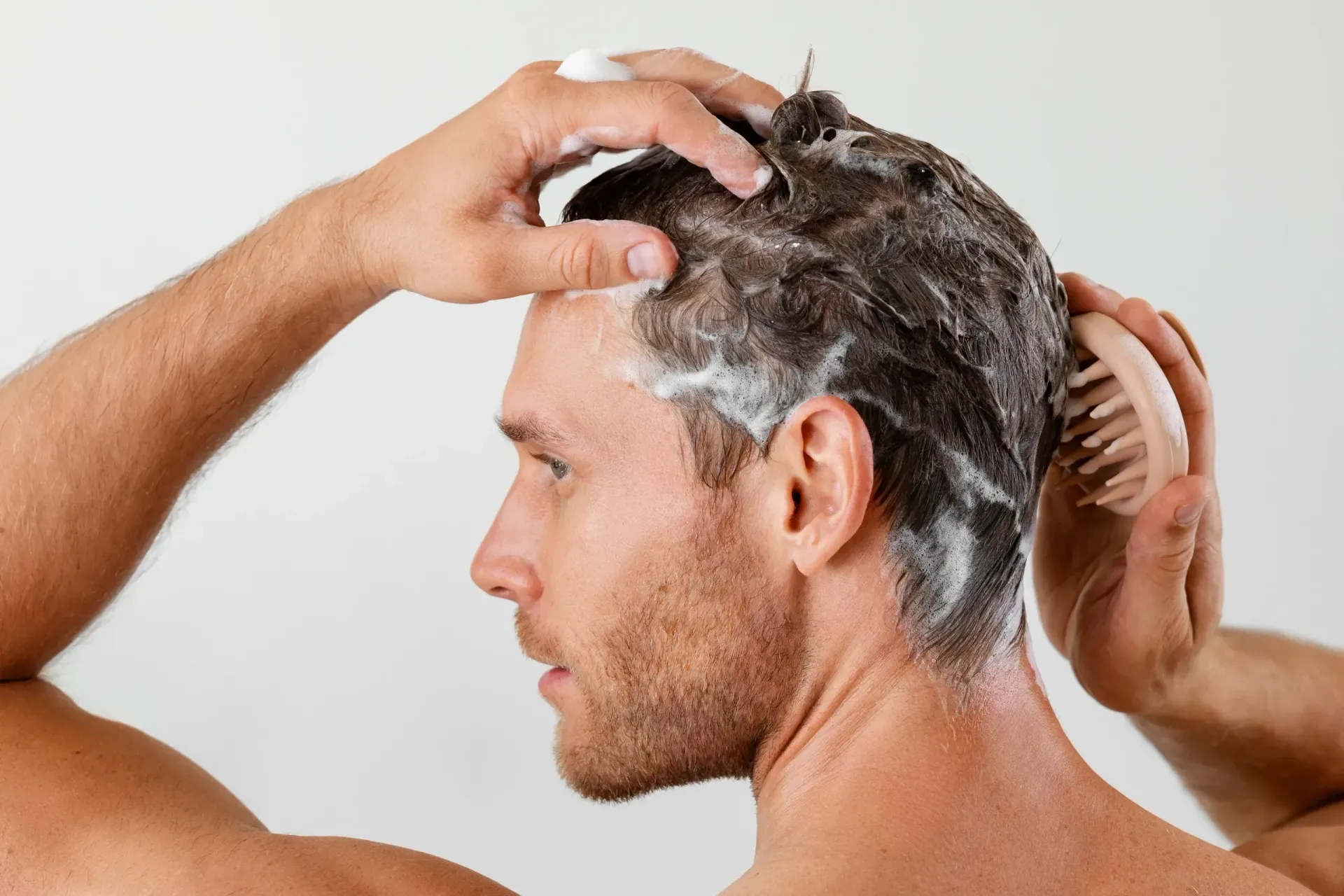 A man is washing his hair in front of a mirror.