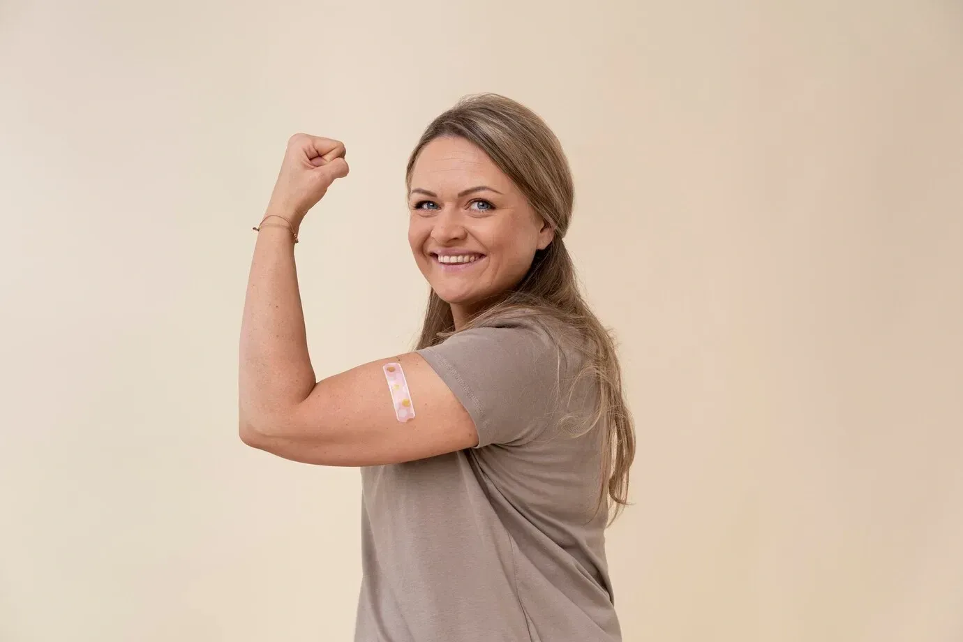 A woman with a bandage on her arm is flexing her muscles.