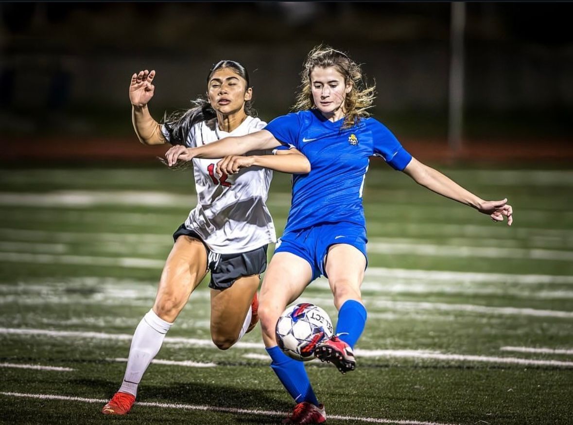 Two players going after a soccer ball