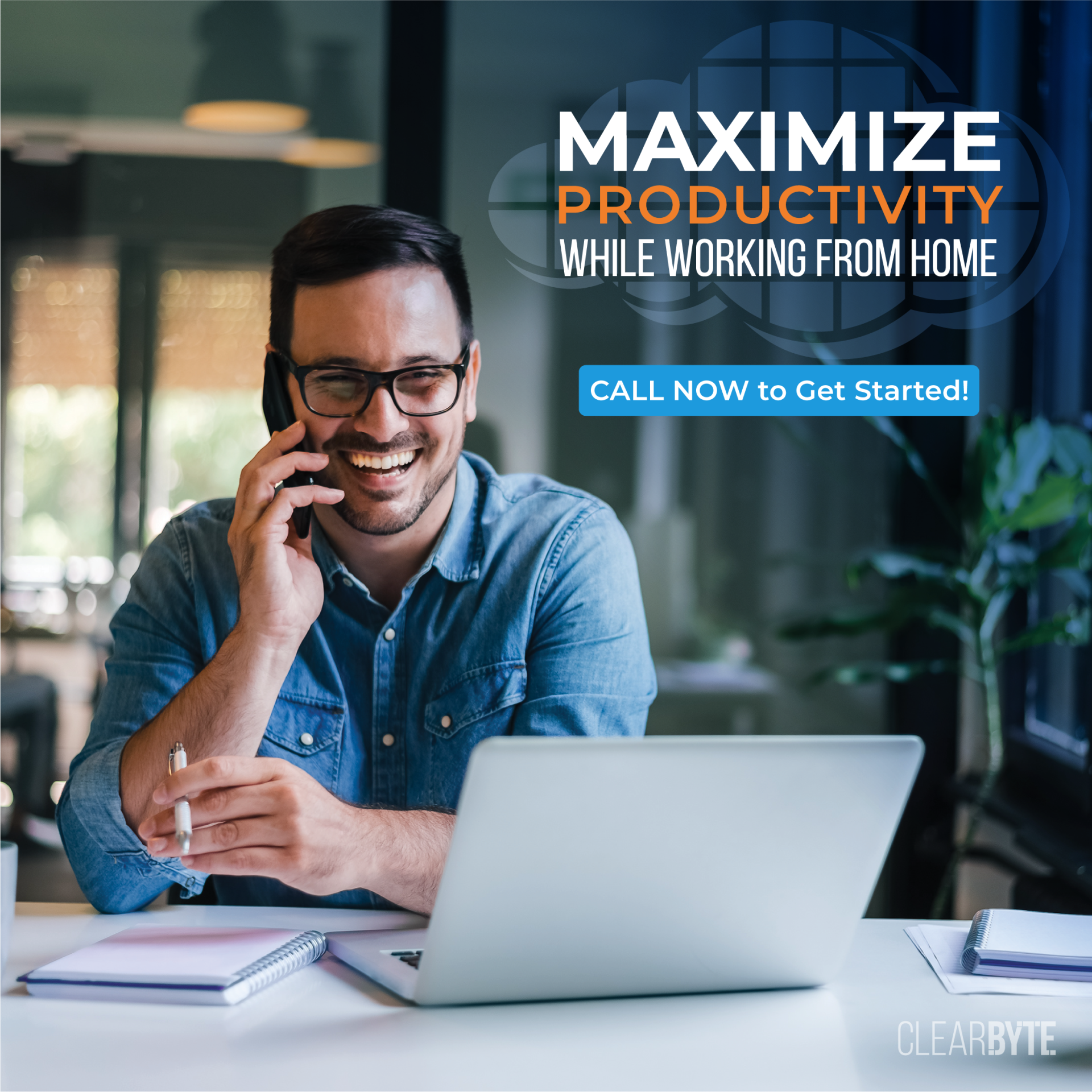 A man is sitting at a desk with a laptop and talking on a cell phone.