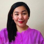 A woman in a purple shirt is smiling for the camera.