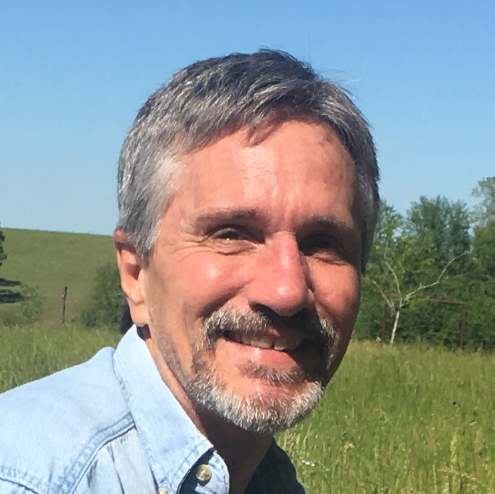 A man with a beard is smiling in a field