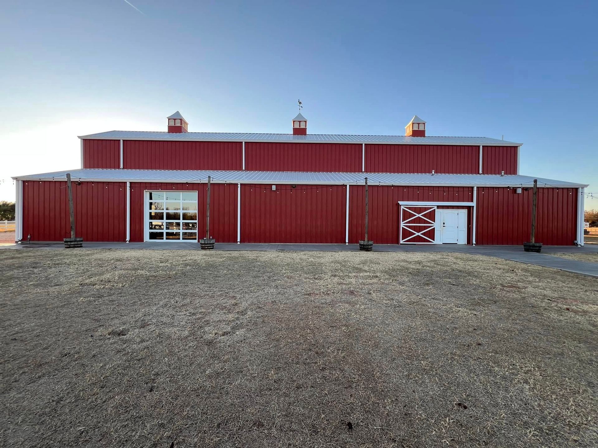 Red barn with white trim and doors under a blue sky.