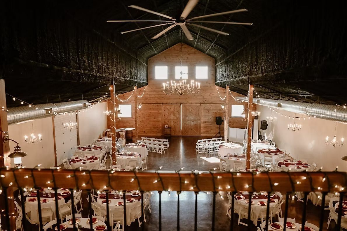 Wedding reception hall with tables set for guests, rustic decor.