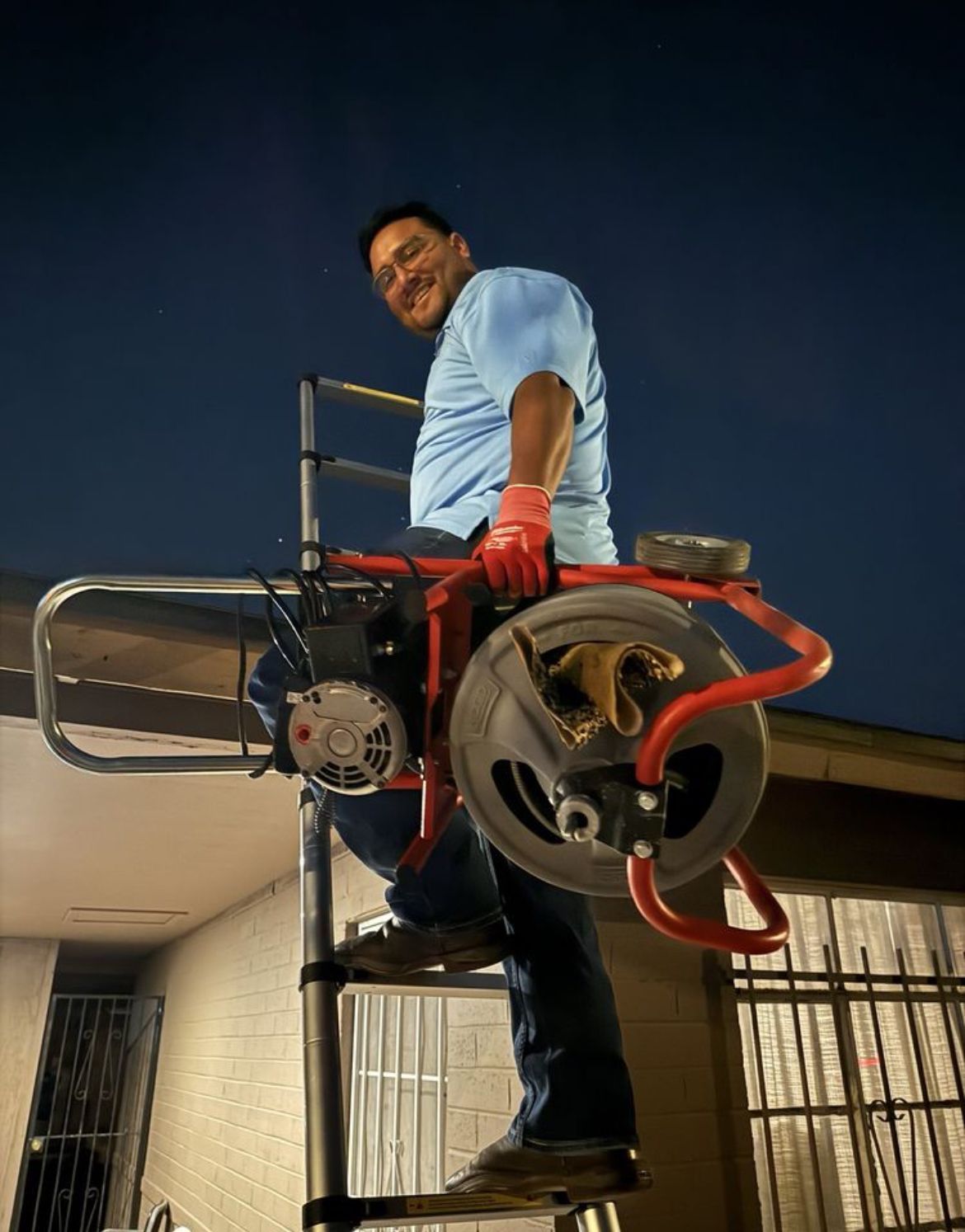 A man is standing on a ladder holding a machine.