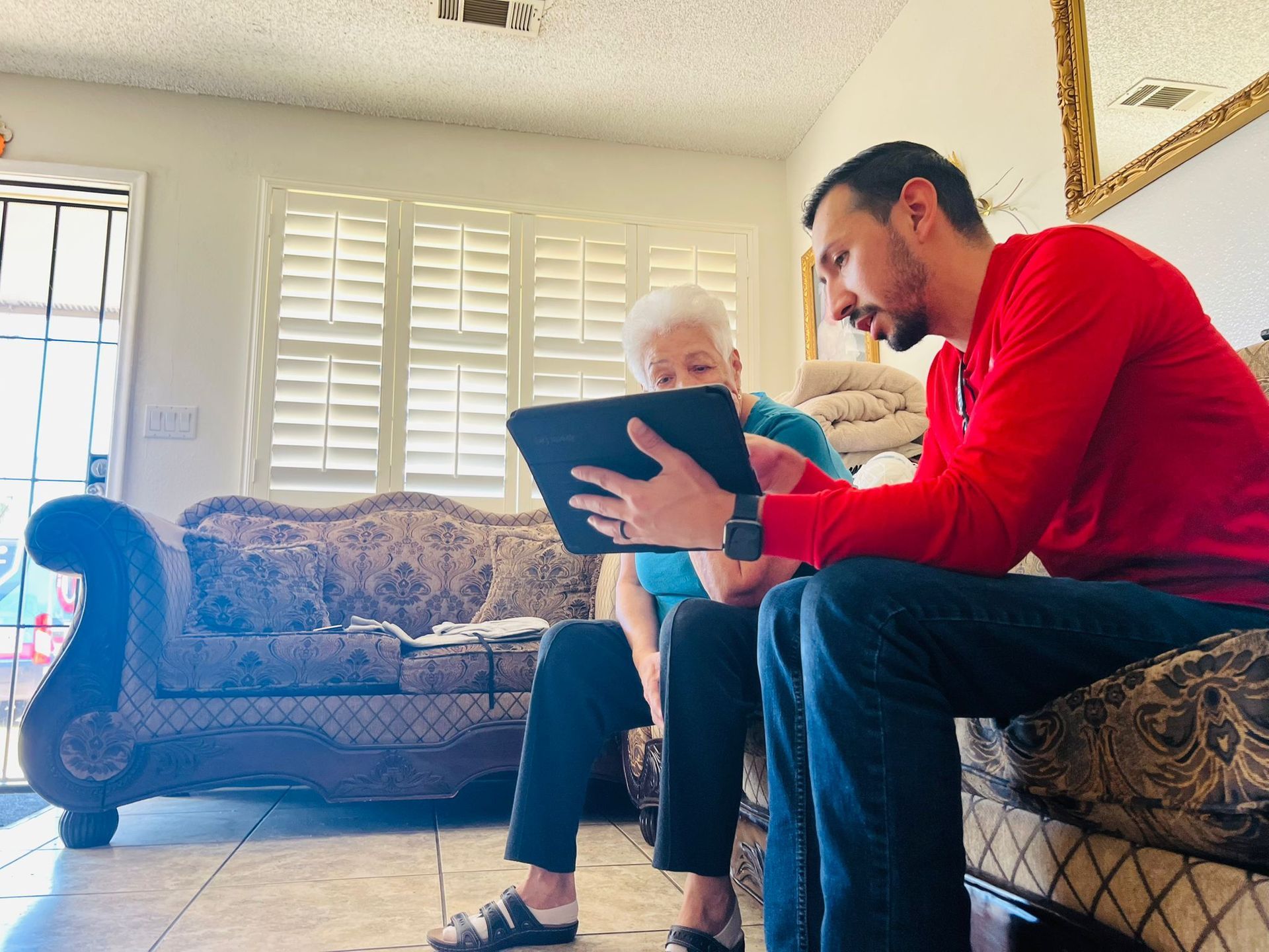 A man and a woman are sitting on a couch looking at a tablet.