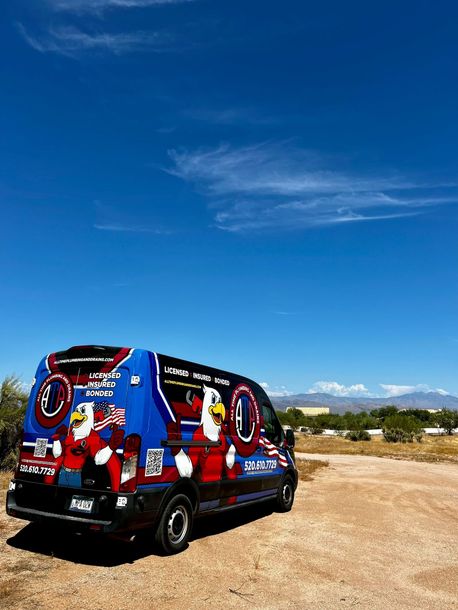 A blue van with an eagle on the side is parked in the woods