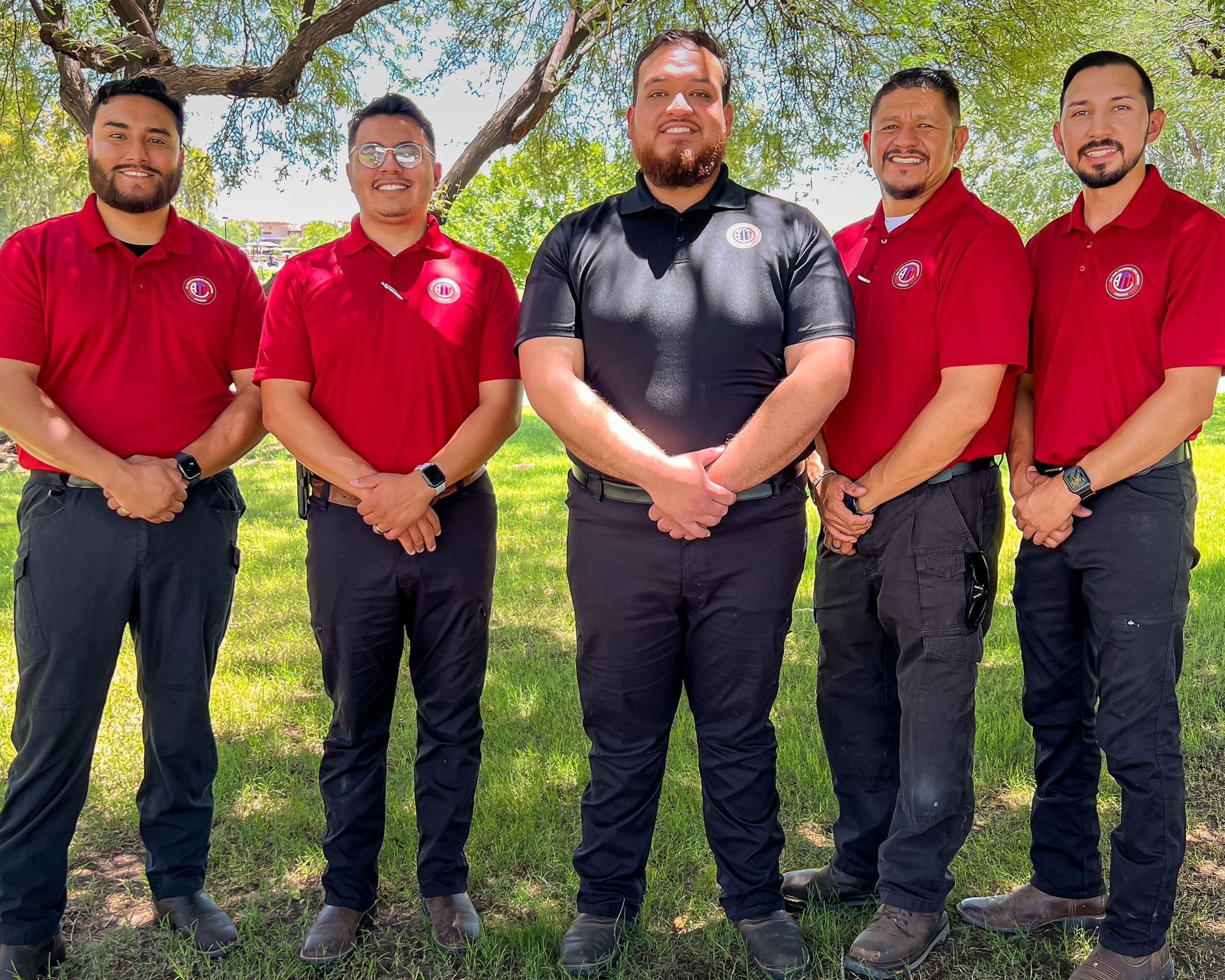 A group of men in red shirts and black pants are posing for a picture.