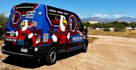 A blue van with an eagle on the side is parked in the woods