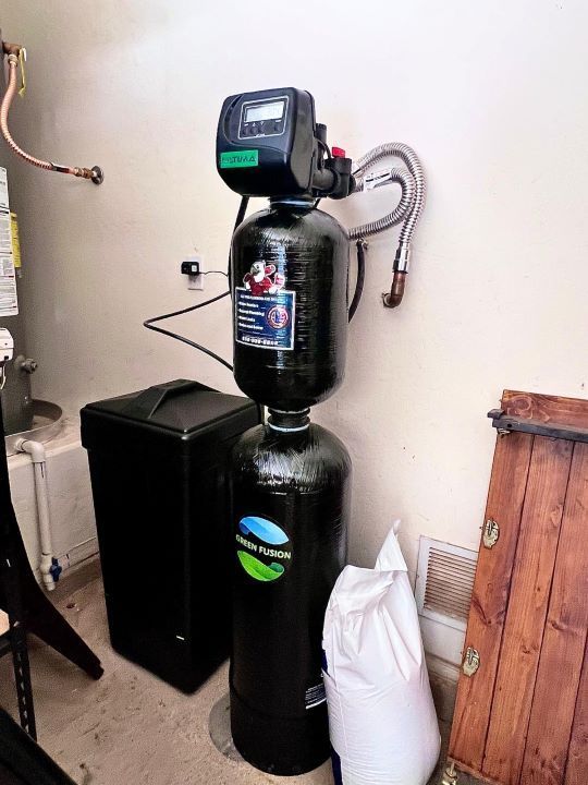 A water softener is sitting in a room next to a water heater.