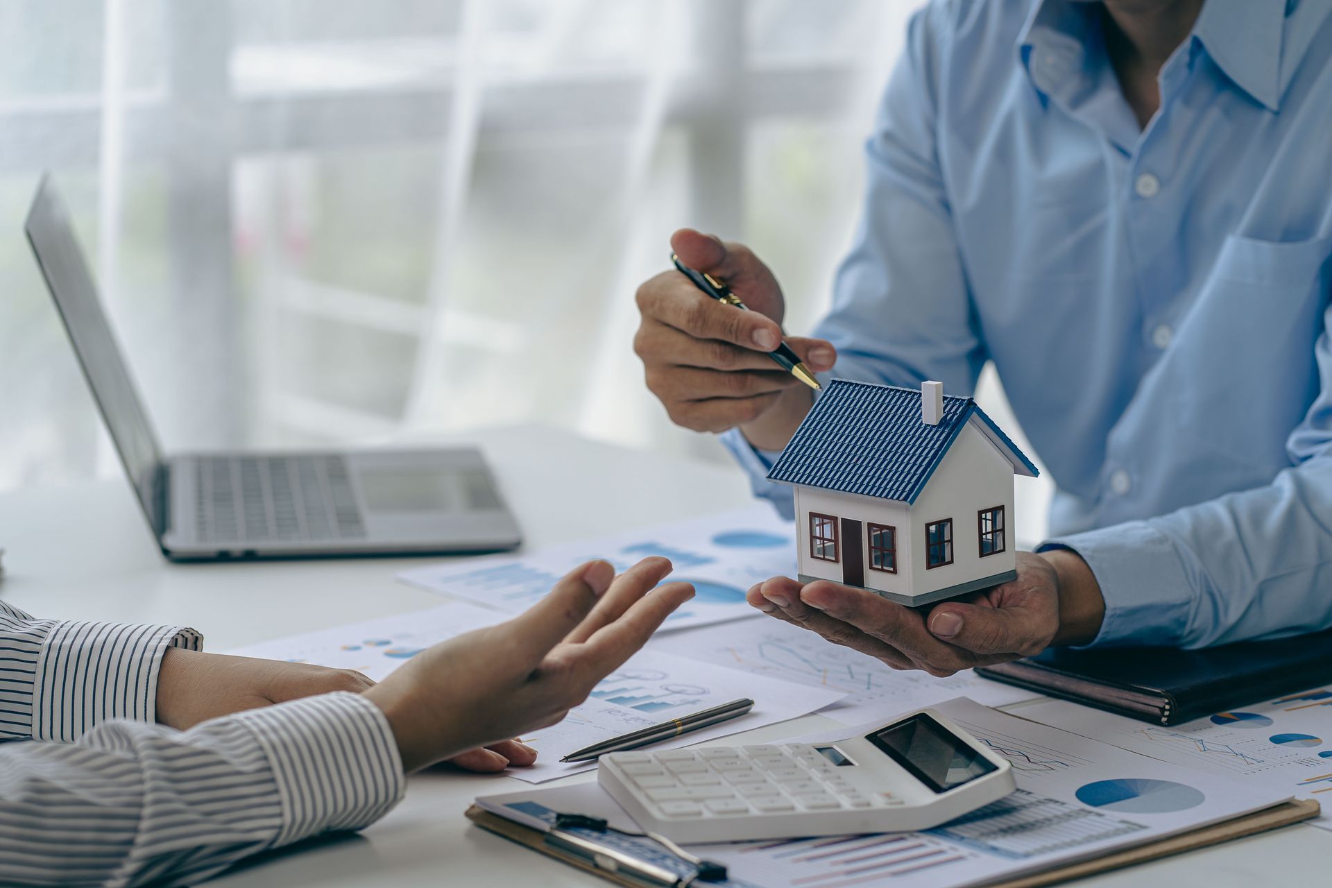 House purchase concept, real estate agent with house model talking to client about buying home insurance and client signing contract under formal contract agreement with real estate law.