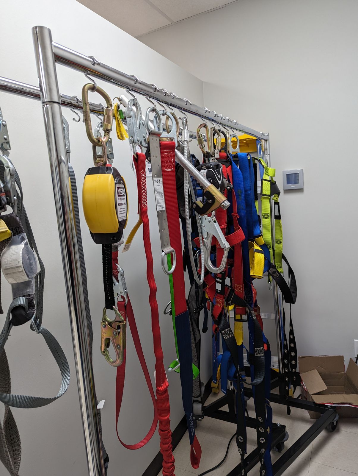 A bunch of safety harnesses are hanging on a rack.
