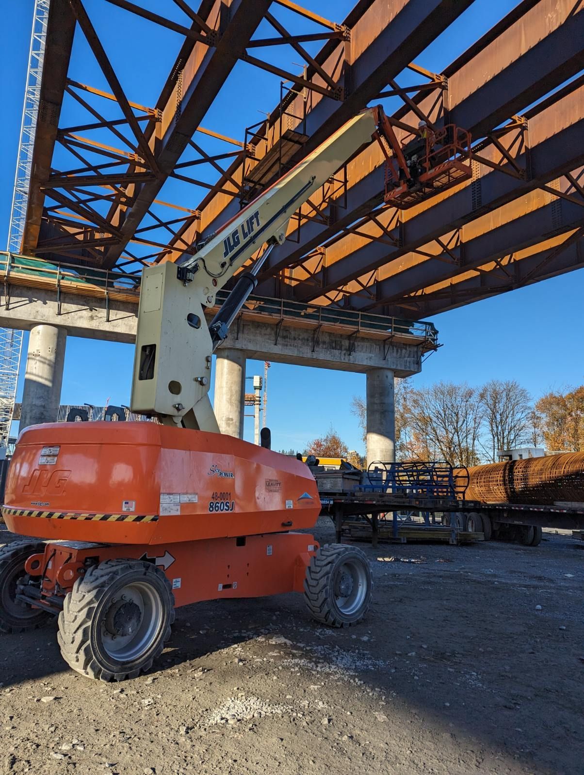 A construction vehicle is parked under a bridge under construction.