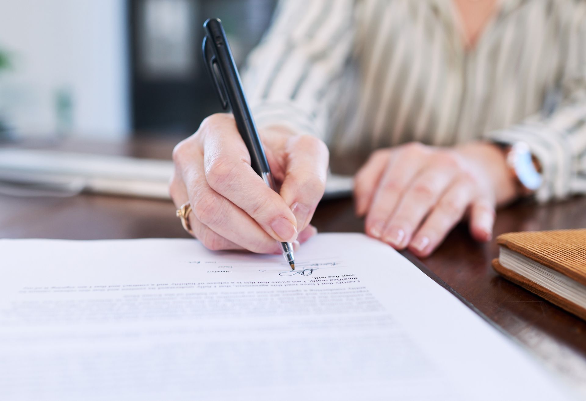 Senior woman writing estate planning documents, close-up of hands, legal and financial planning for seniors