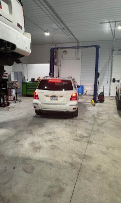 A white suv is parked in a garage next to a lift.