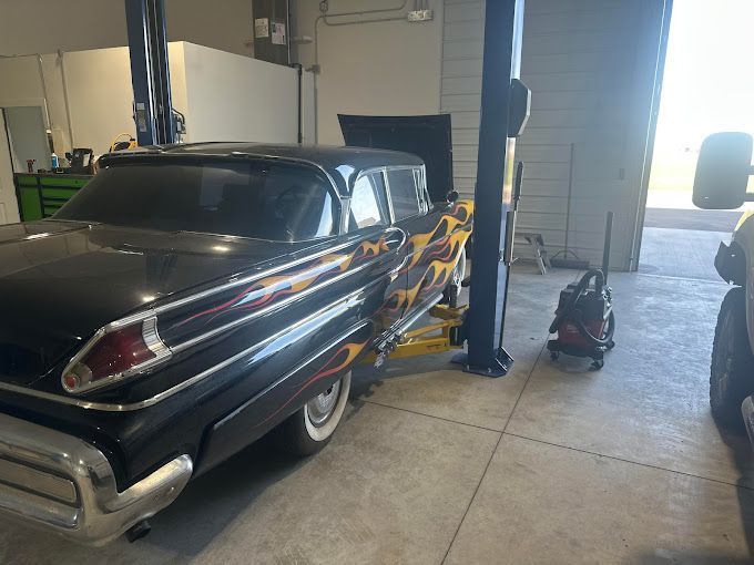 A black car is parked on a lift in a garage.