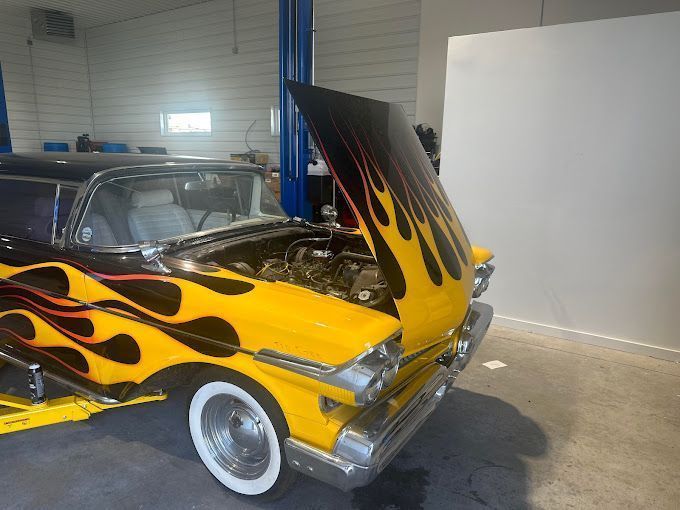 A yellow car with flames painted on it is parked in a garage.