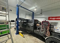 A truck is sitting on a lift in a garage.