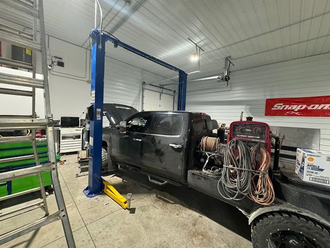 A truck is sitting on a lift in a garage.