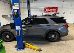 A police car is parked on a lift in a garage.