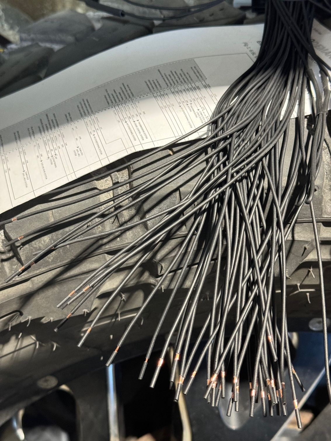 A bunch of wires are coming out of the hood of a car