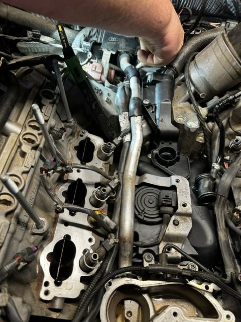 A person is working on a car engine with a screwdriver.