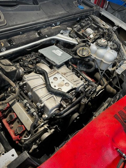 A close up of a car engine with the hood open