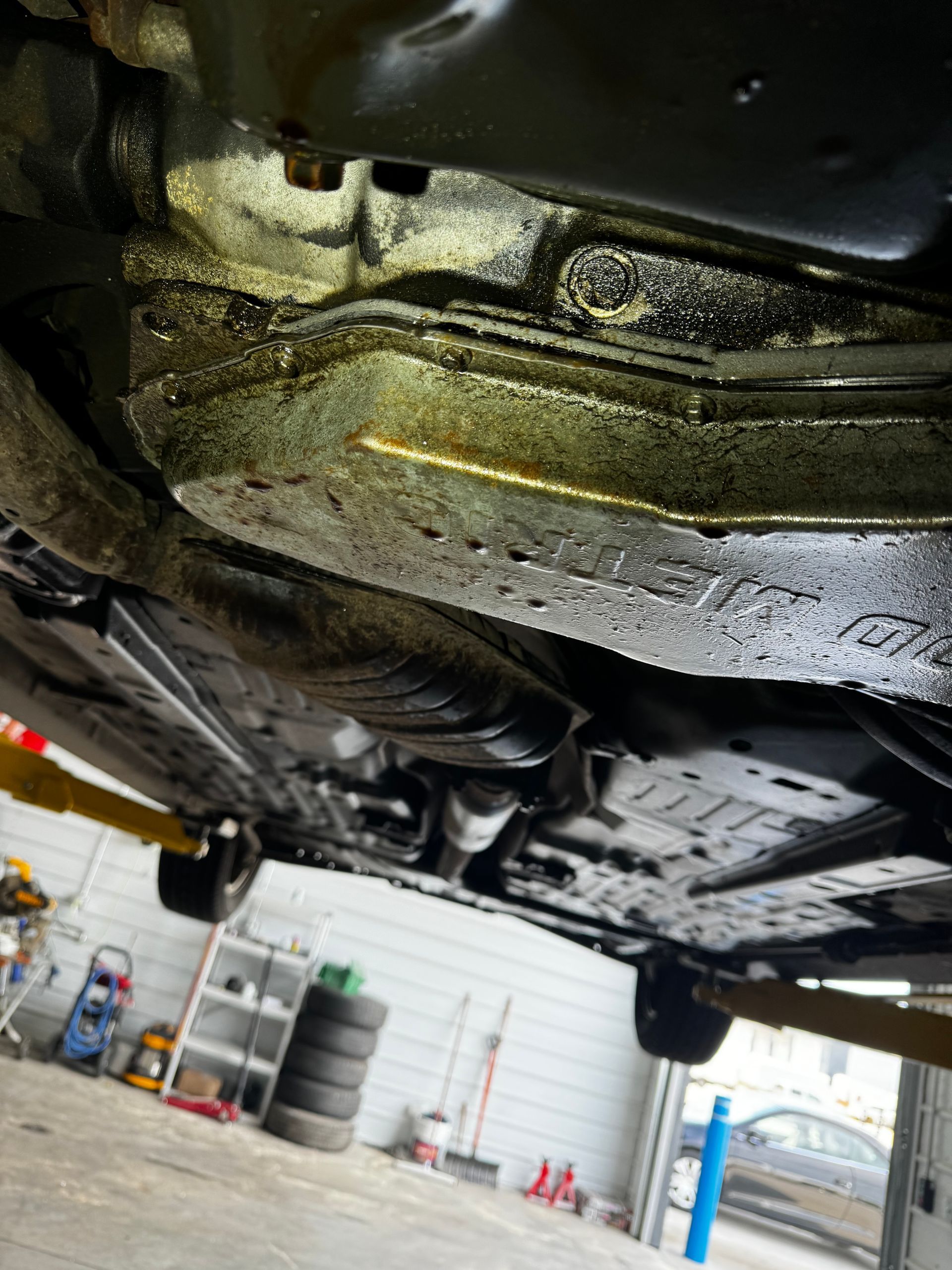 The underside of a car is shown in a garage.