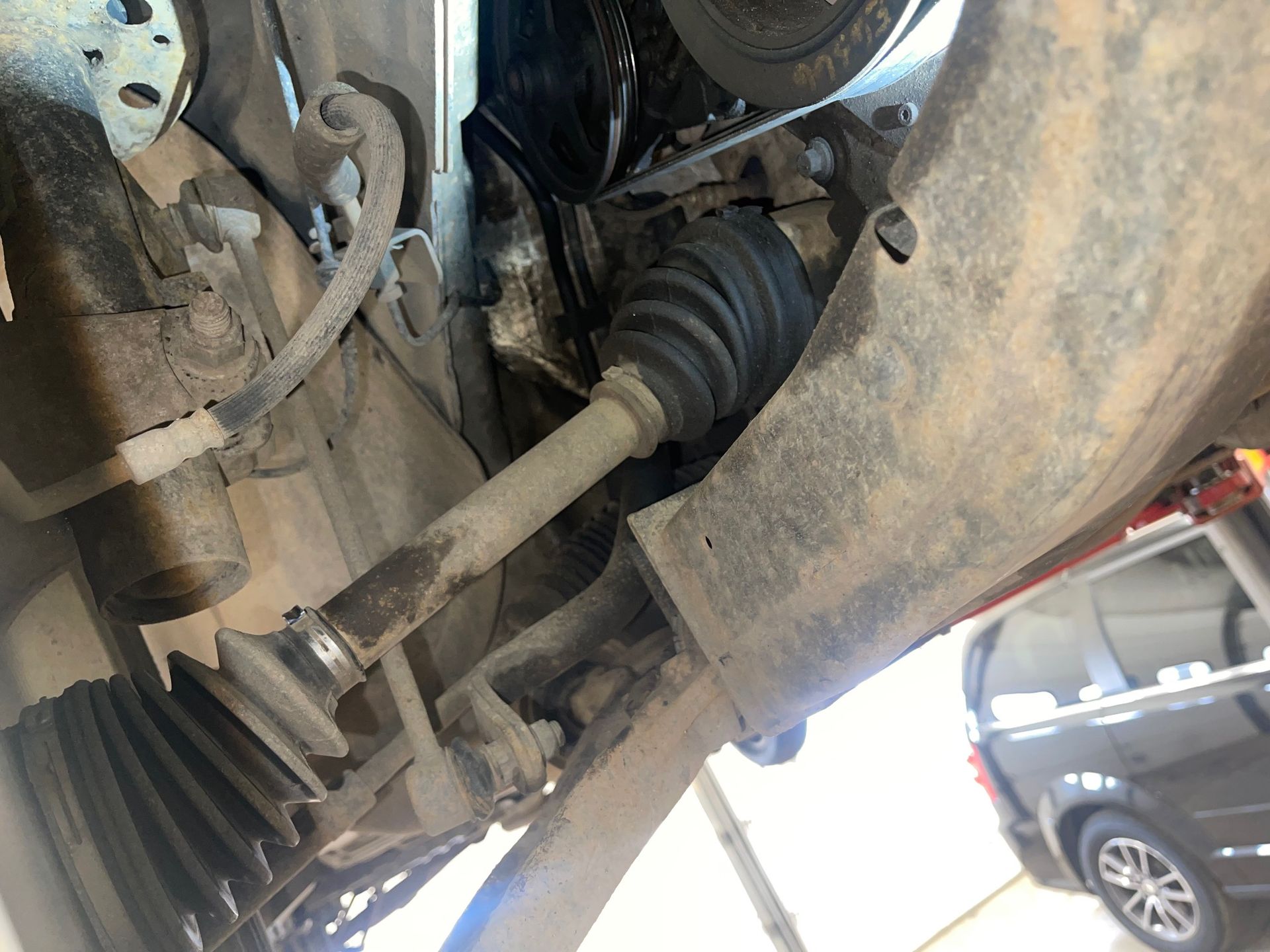 A close up of a car 's drive shaft in a garage.