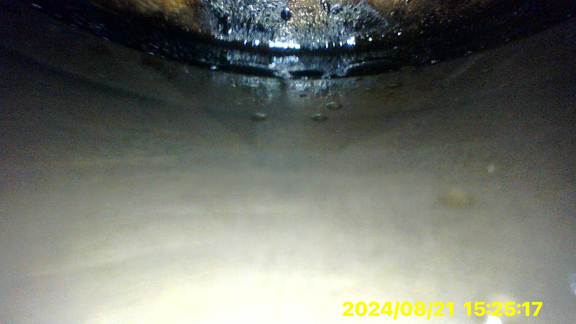 A close up of a dirty pipe with water coming out of it.