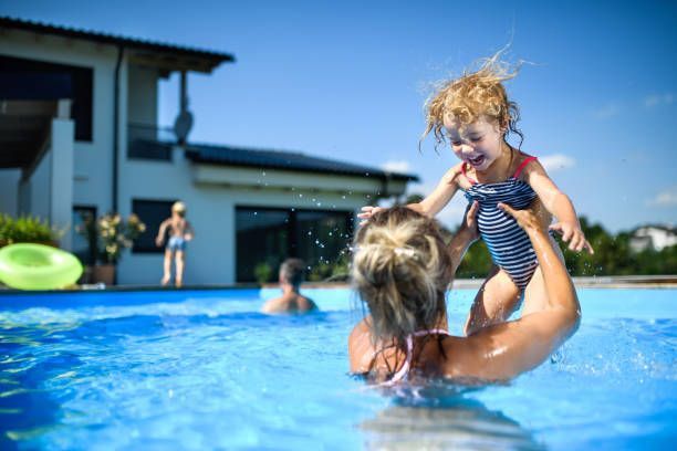 A woman is holding a little girl in her arms in a swimming pool.