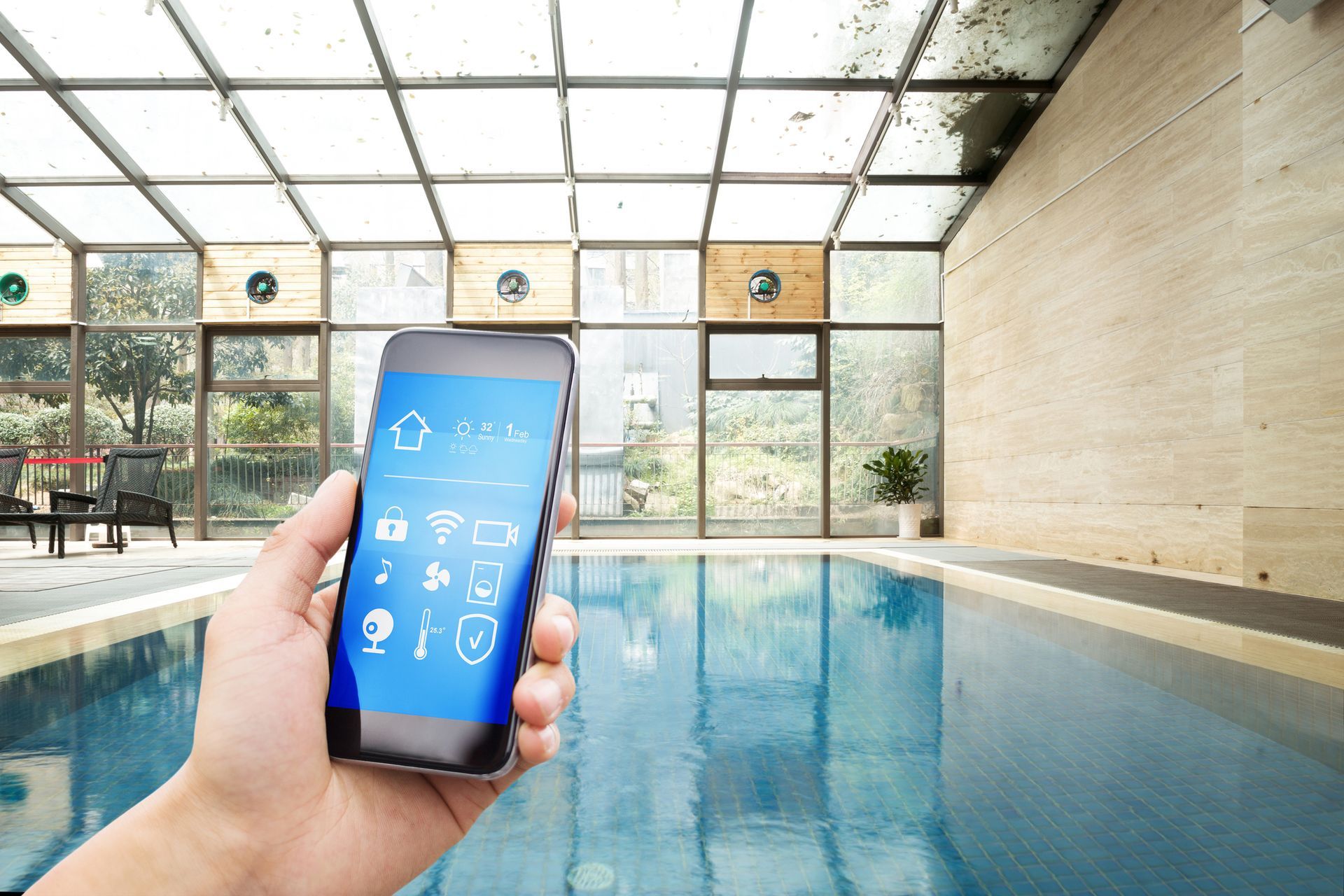 A person is holding a smart phone in front of a swimming pool.