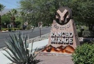 Rancho Mirage city entrance sign with ram logo. Desert landscape with trees and mountains in the background. Rancho Mirage city entrance sign with ram logo. Desert landscape with trees and mountains in the background.