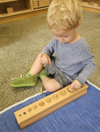 Montessori child working with knobbed cylinders