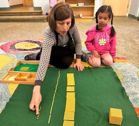 Montessori guide and child working with math materials
