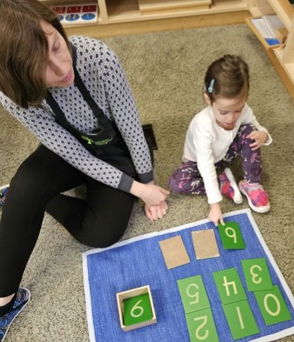 Montessori guide and child working with math materials