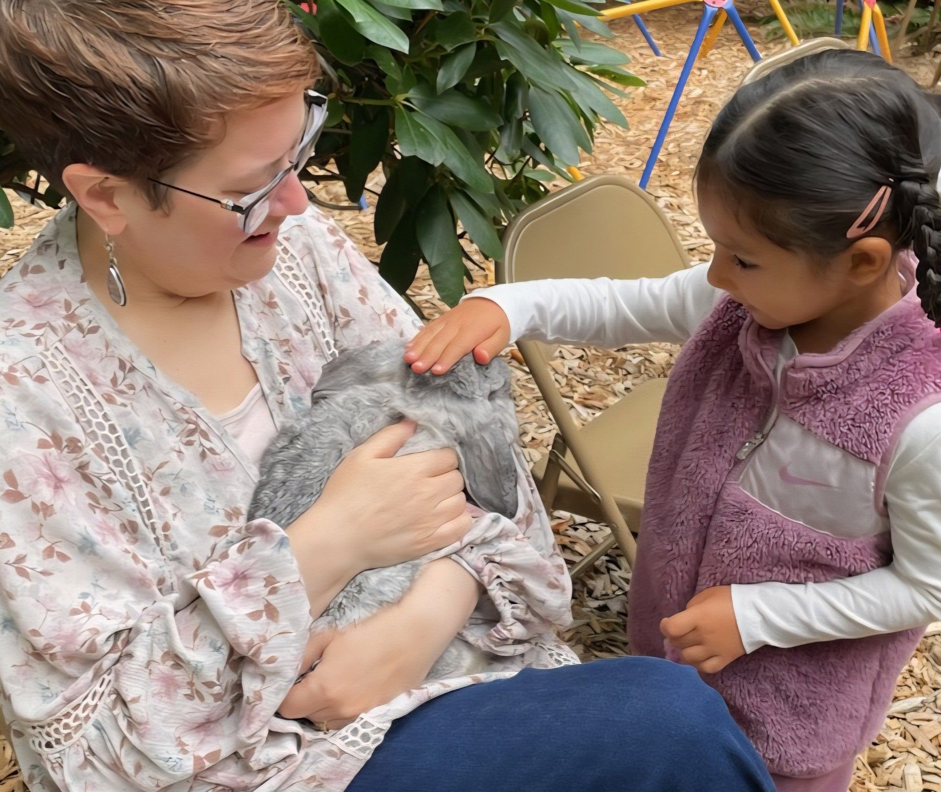 Montessori guide and children in the playground petting a rabbit
