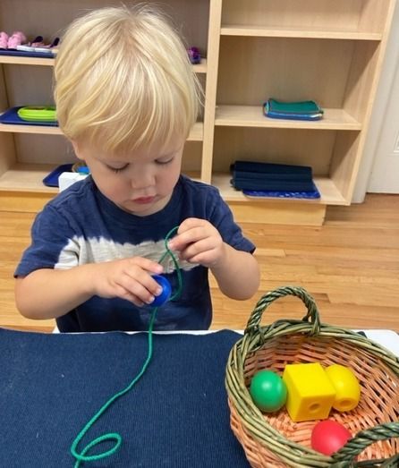 Montessori child working on bead stringing