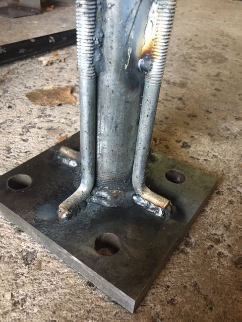 Welded metal base with threaded rods, bolted to a square metal plate.