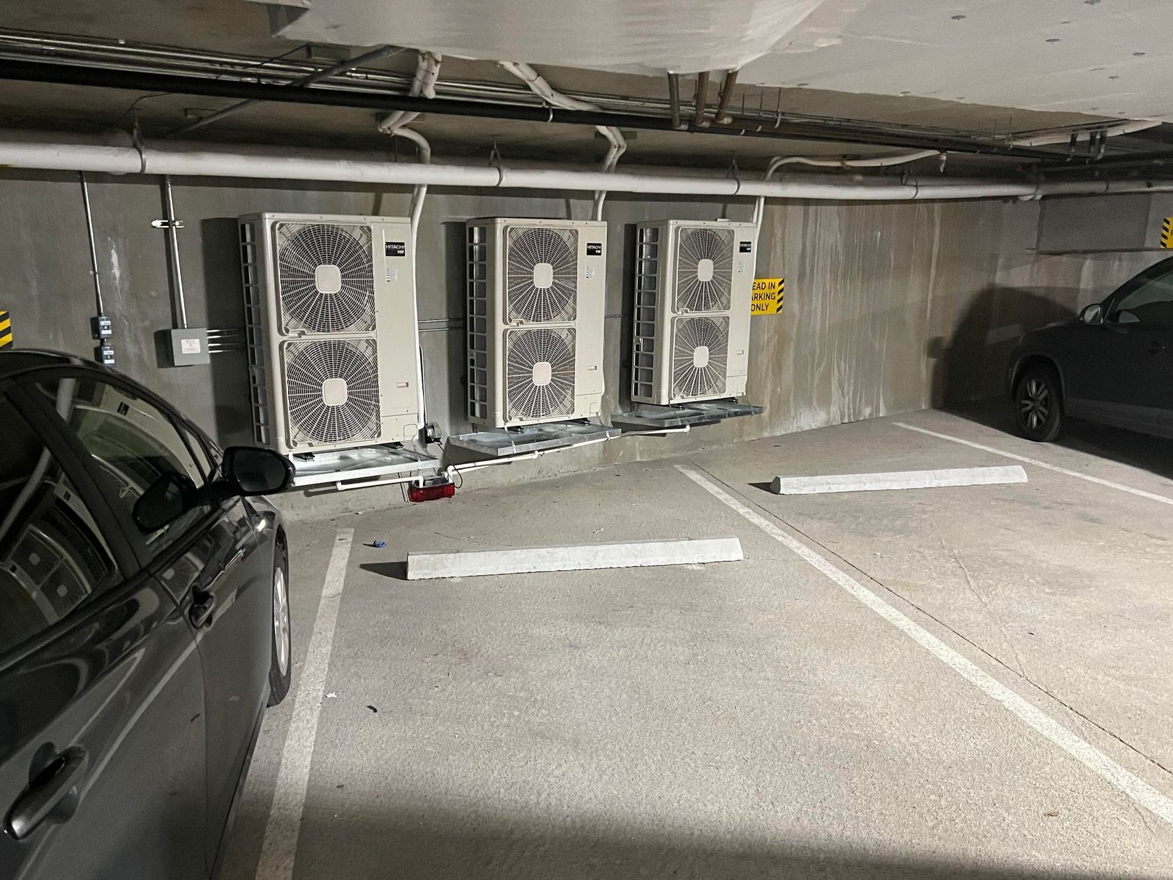 A row of air conditioners are sitting outside of a brick building installed by Pro Temp.