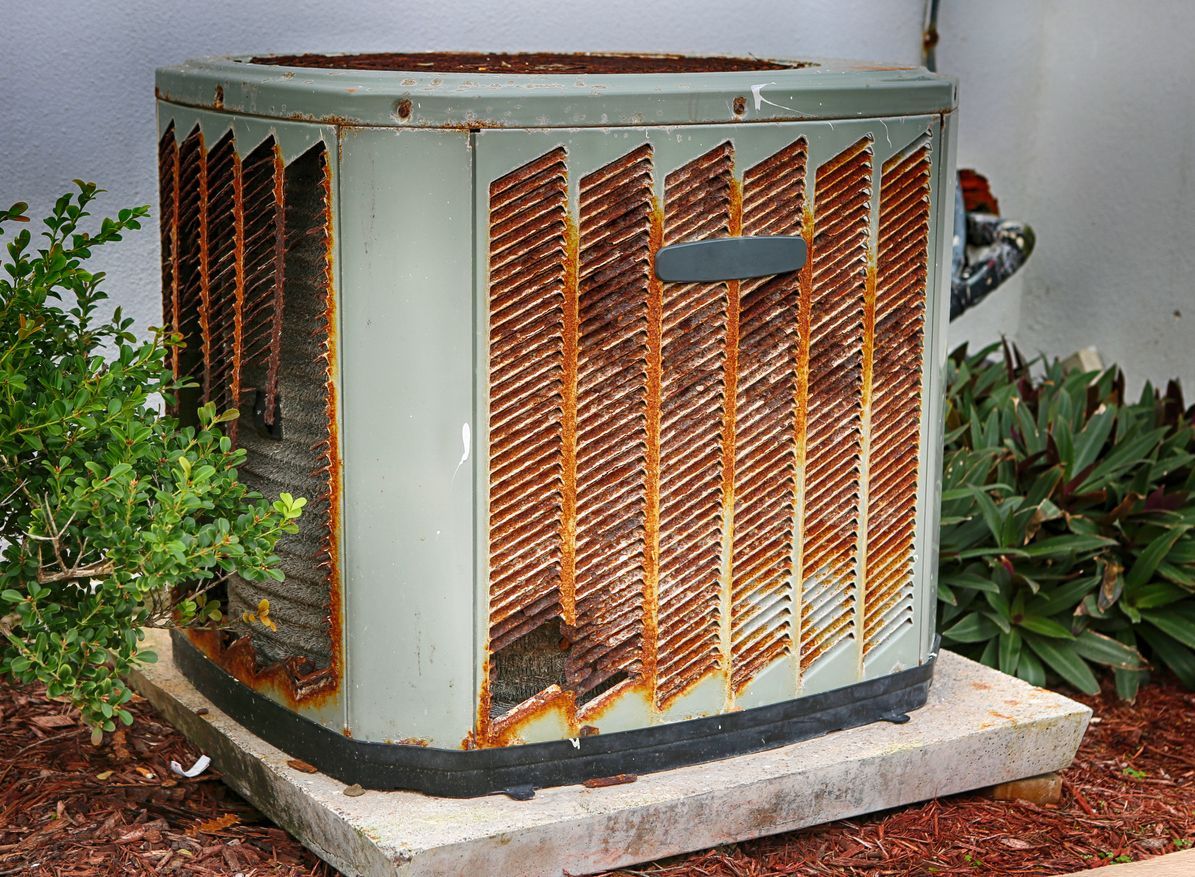 HVAC technician inspecting an older air conditioner unit in a residential backyard.