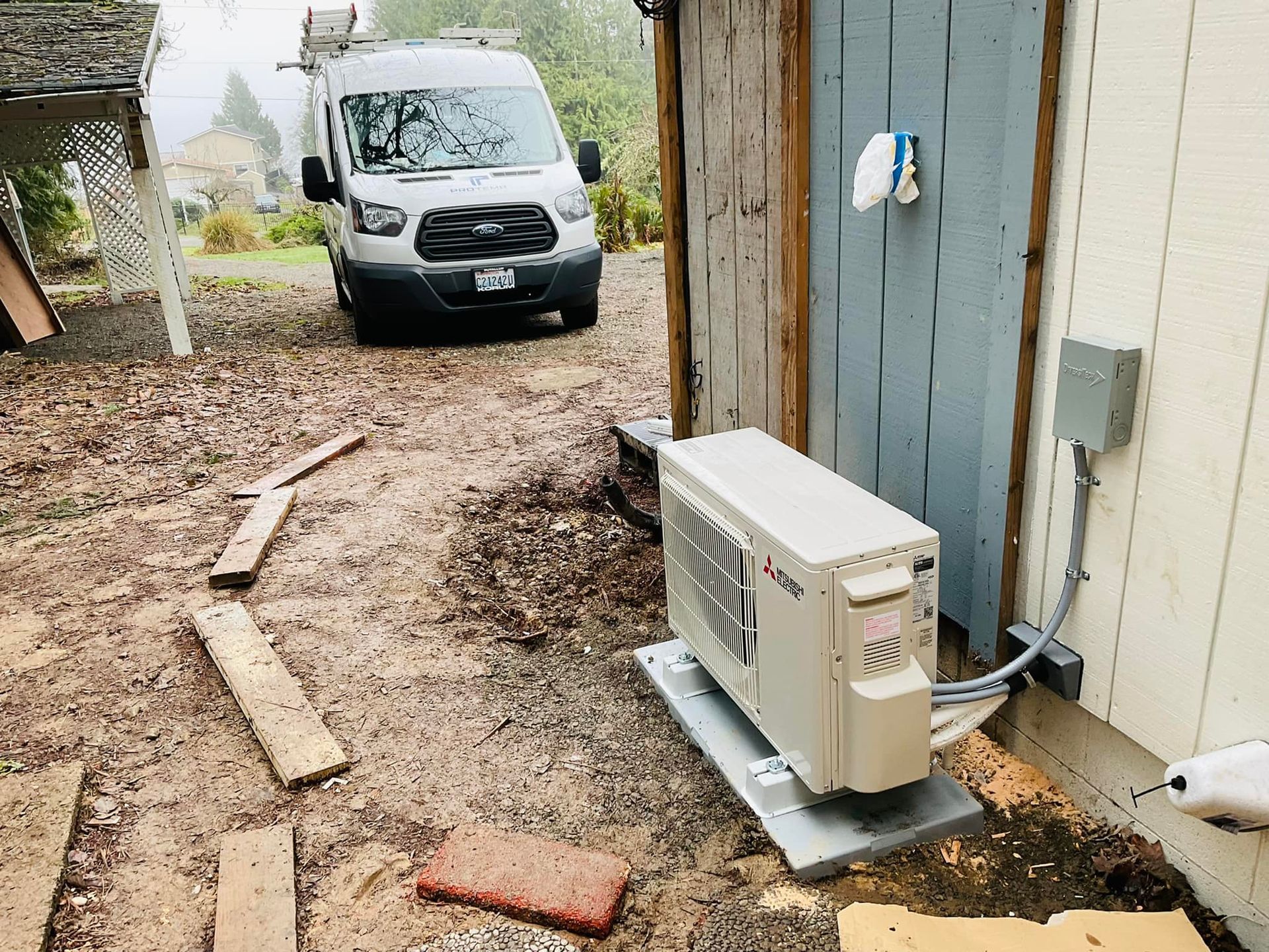 A van is parked in front of a building next to a large air conditioner.
