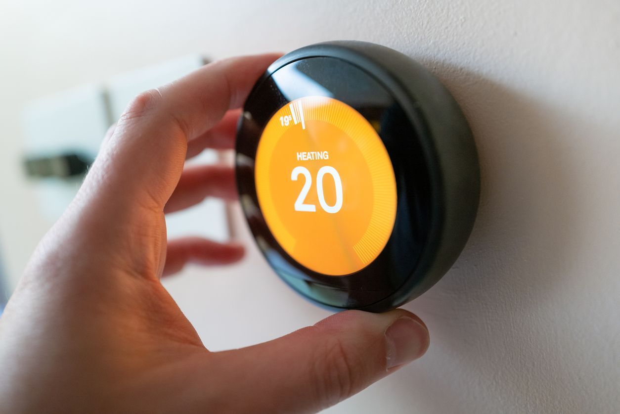 A person is adjusting a smart thermostat on a wall installed by Pro Temp.